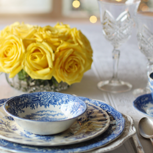 A table setup with plate ware and a yellow bouquet of flowers.