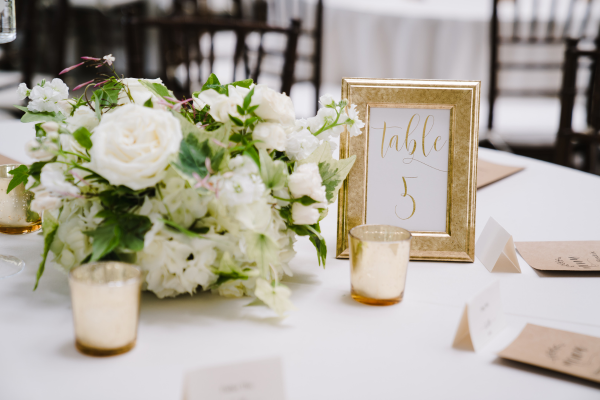 A setup wedding table with reservation numbers and a bouquet of flowers. 